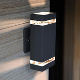 Black outdoor wall light fixture on a stone wall